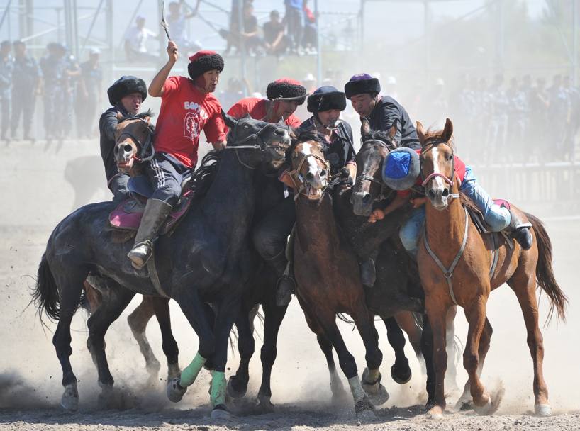 Uomini e cavalli durante una Bukashi nel Kyrgyzstan. Si tratta di uno sport tradizionale molto diffuso, giocato con una carcassa di capra, in cui  ppermesso anche di colpire gli avversari (Afp/Vyacheslav Oseledko)